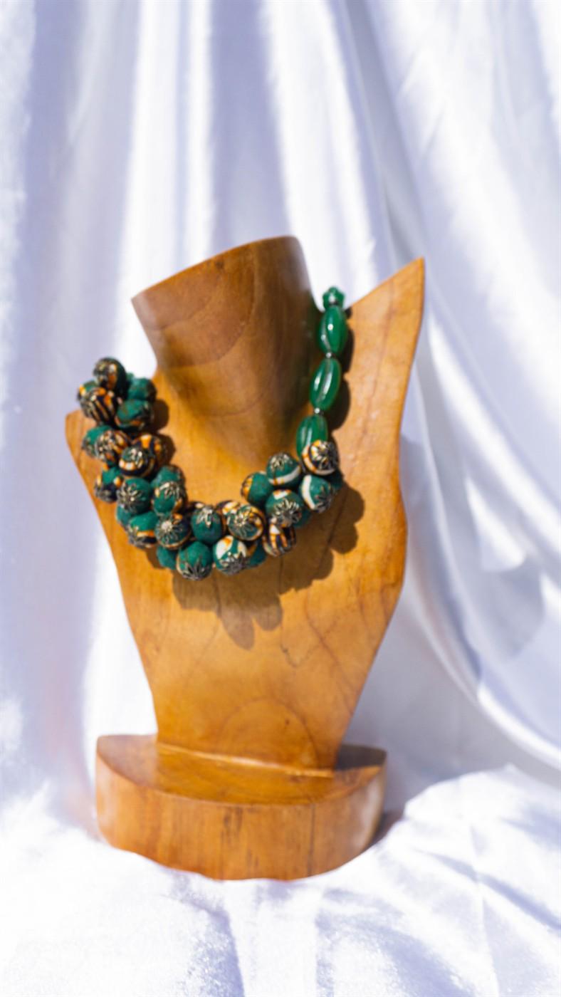 Kalung Aresha Batik dengan manik kain batik hijau dan manik kaca pada manekin kayu.